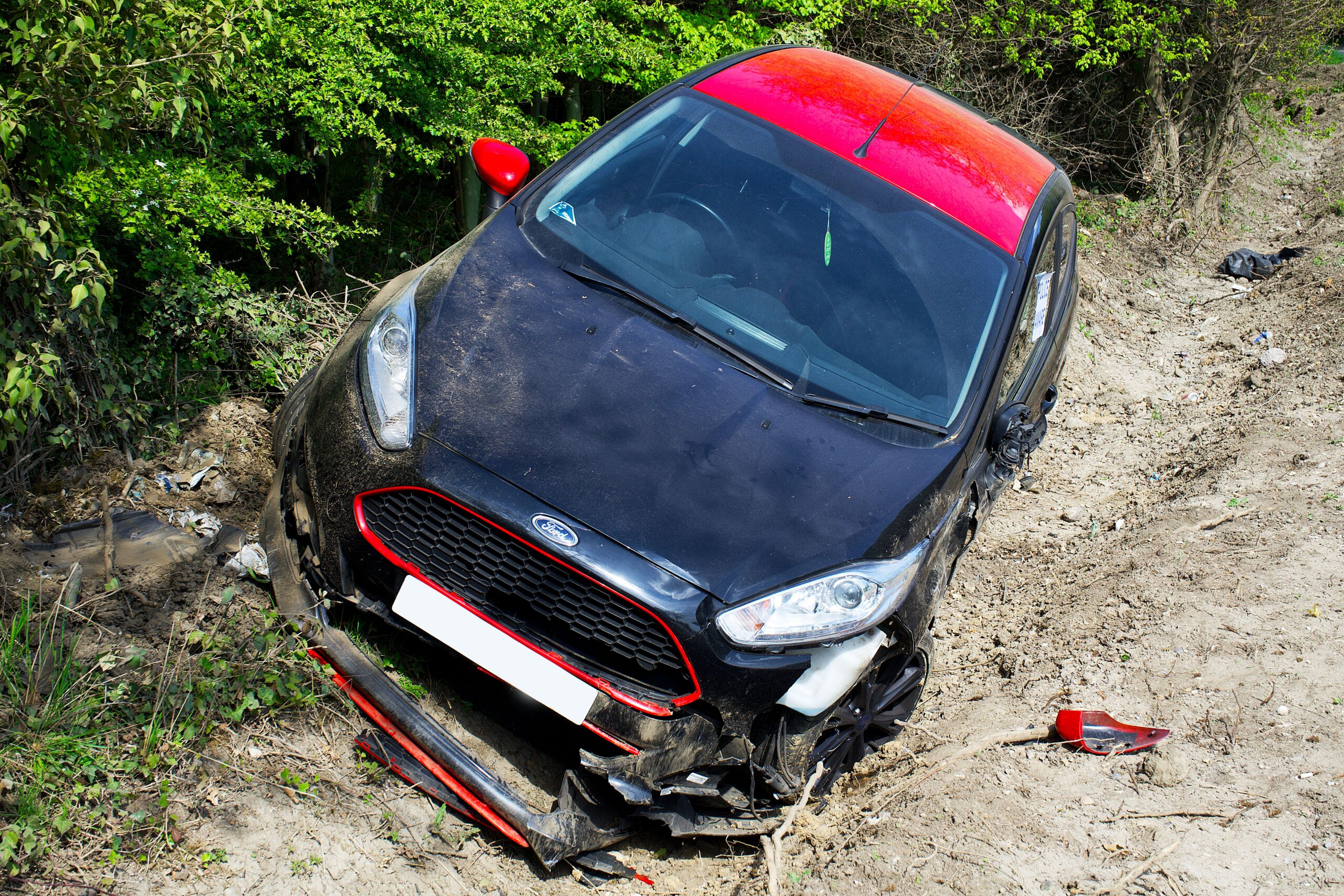 red and black car in ditch after accident